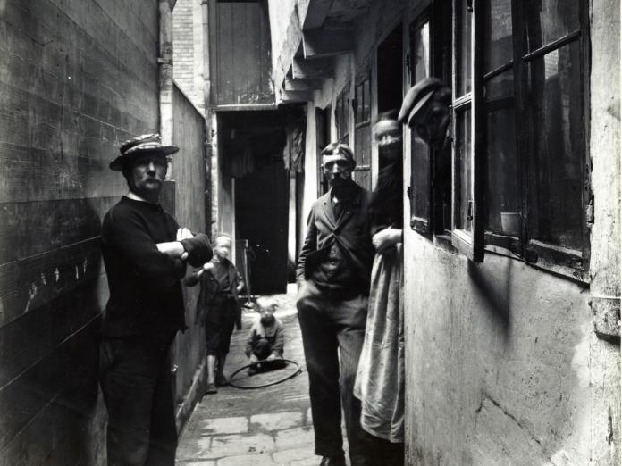 Sort-hvid-foto af personer i gangen langs Adelgade 71, august 1898. 